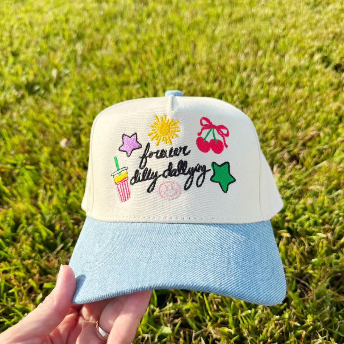 Cap with colorful designs and text held in front of a grassy background