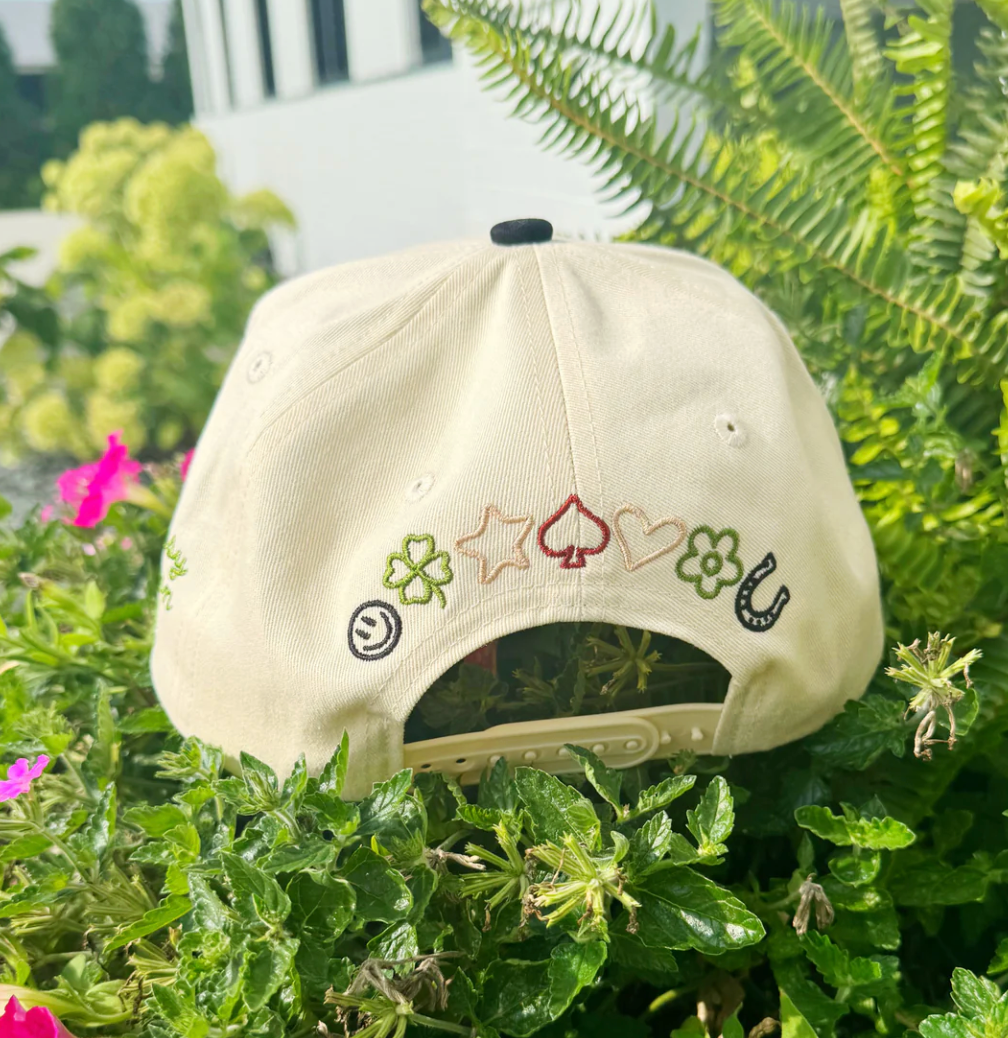 Beige cap with embroidered symbols on a green plant background