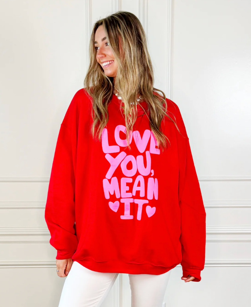 Person wearing a red sweatshirt with pink text against a white background